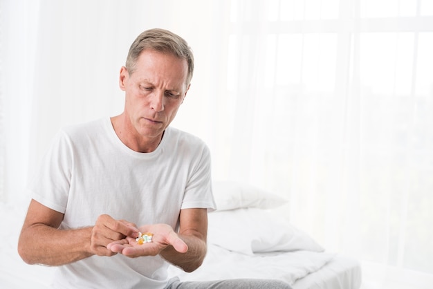 Free photo medium shot man with pills in the bedroom