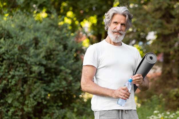 Medium shot man with yoga mat and water