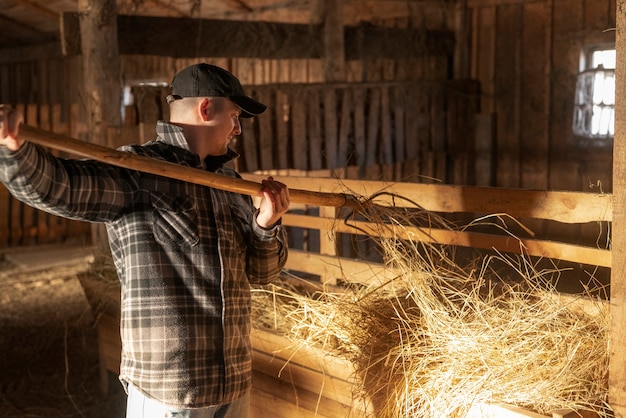 Medium shot man working in barn rural life