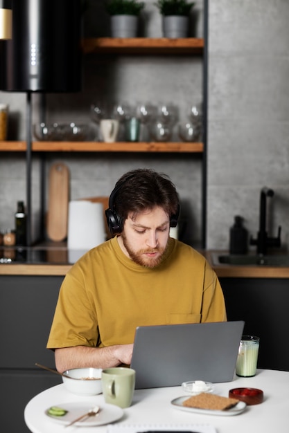 Free photo medium shot man working on laptop at home