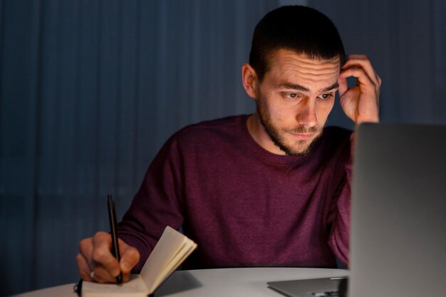 Medium shot man working late at night on laptop