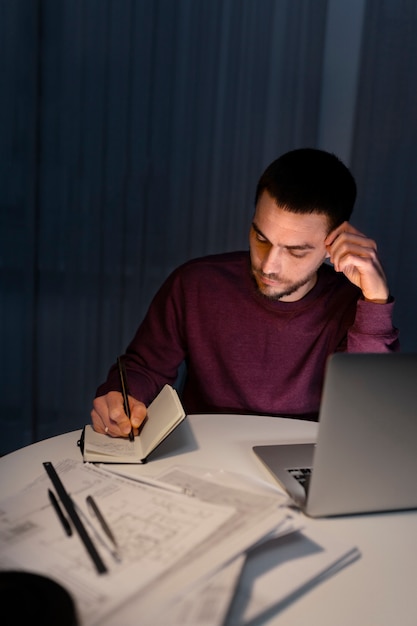 Medium shot man working late at night on laptop