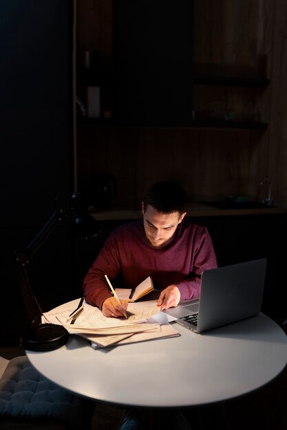 Medium shot man working late at night on laptop