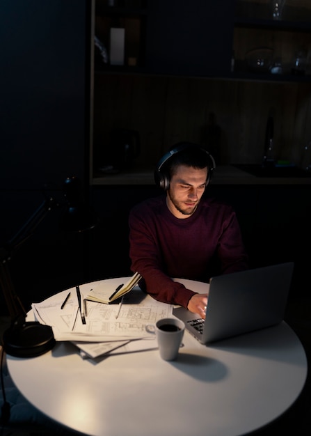 Medium shot man working late at night on laptop