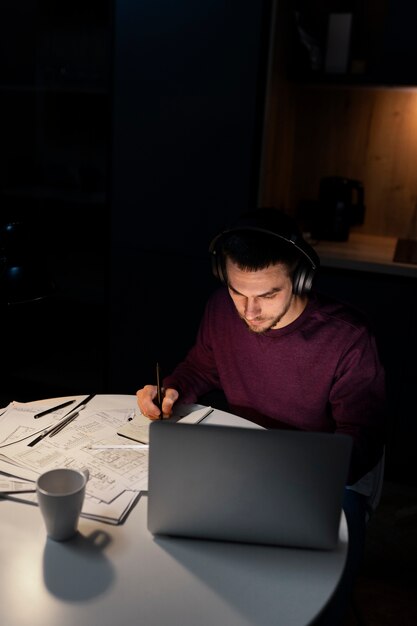 Medium shot man working late at night on laptop