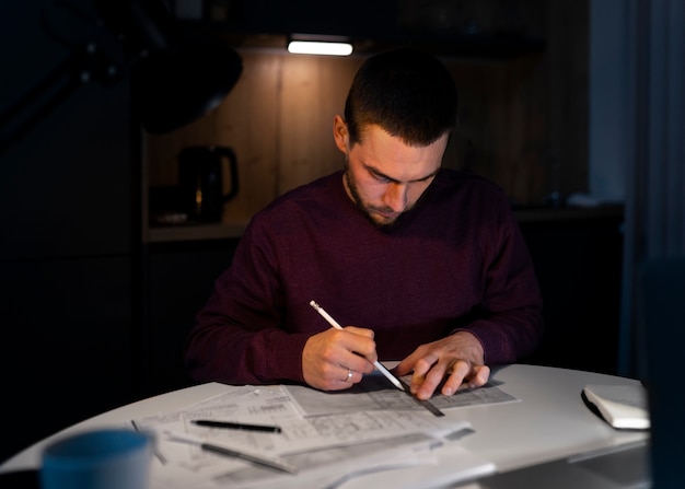 Medium shot man working late at night on laptop