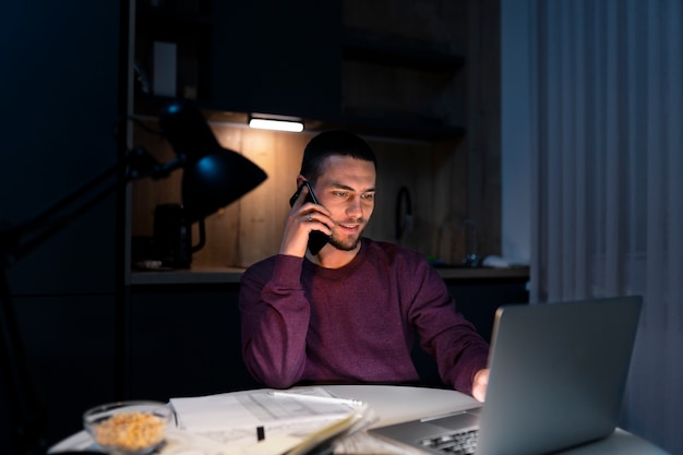 Medium shot man working late at night on laptop