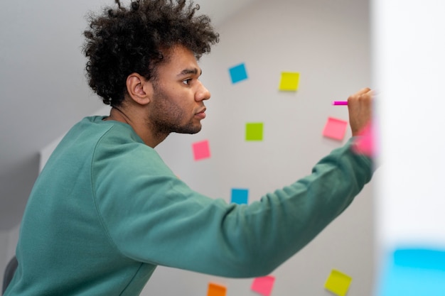 Medium shot man writing on post it at work