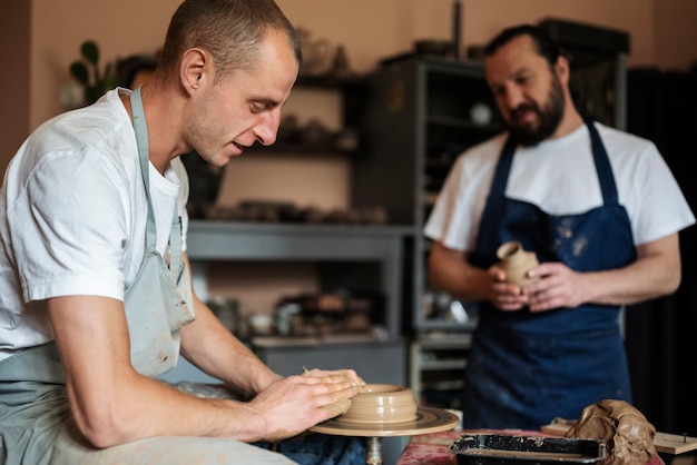 Free photo medium shot men doing pottery