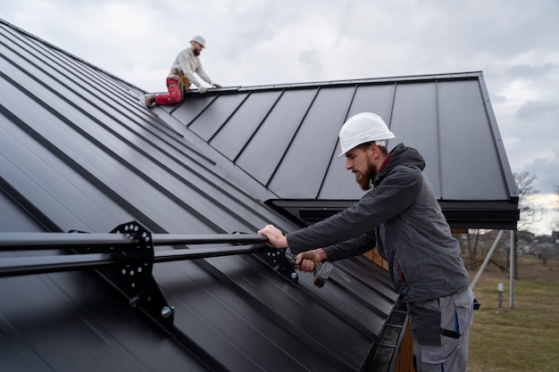 Free photo medium shot men working on roof together