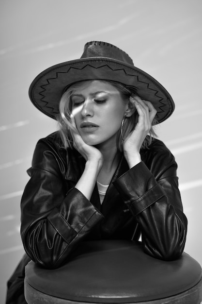 Free photo medium shot model posing with hat black and white