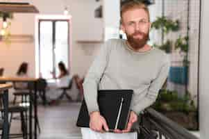 Free photo medium shot modern man holding his laptop and notebook