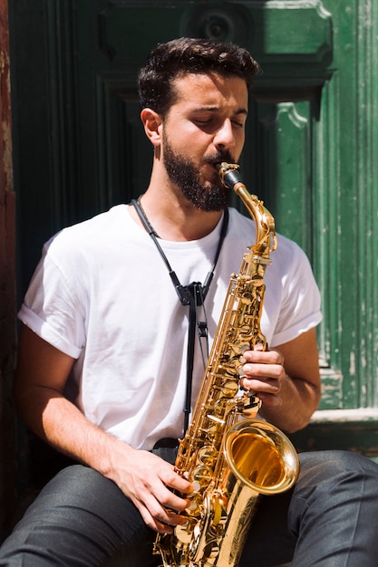 Free photo medium shot musician sitting and playing the sax