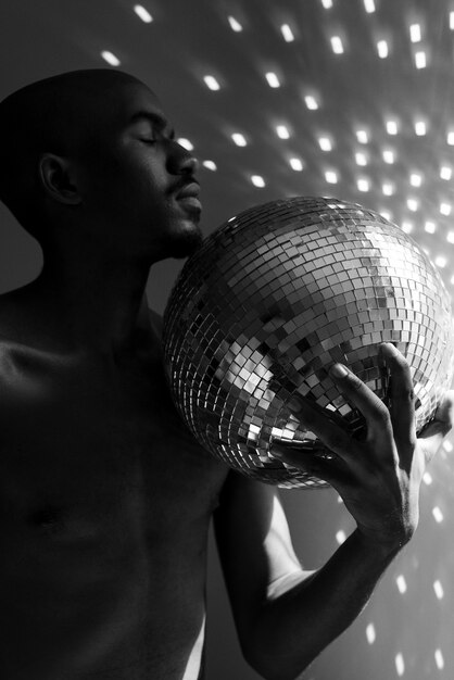 Medium shot naked man posing with disco ball