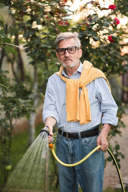 Free photo medium shot old man watering plants