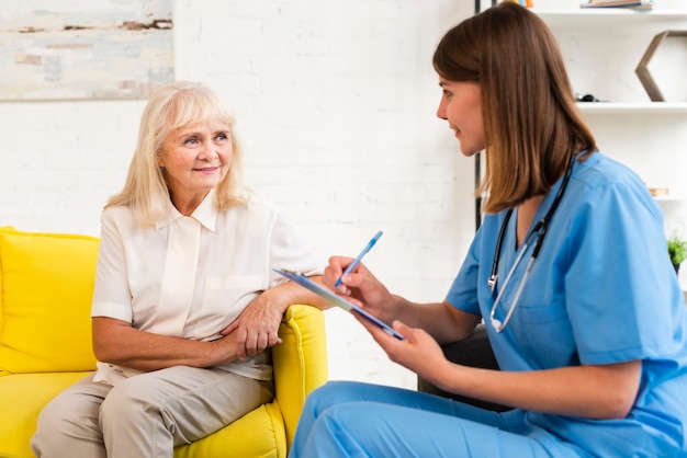 Medium shot old woman and caregiver talking