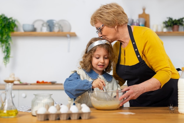 Free Photo medium shot old woman and girl in kitchen