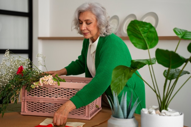 Medium shot old woman taking care of plants