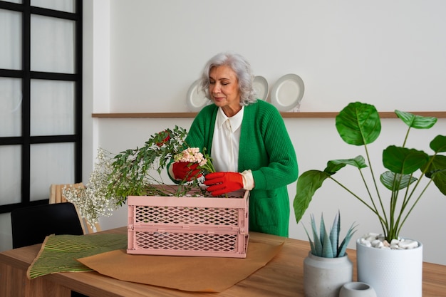 Medium shot old woman taking care of plants