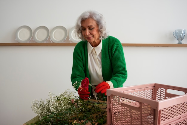 Medium shot old woman taking care of plants