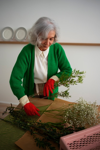 Medium shot old woman taking care of plants