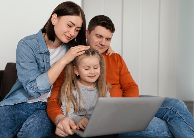 Medium shot parents and kid with laptop