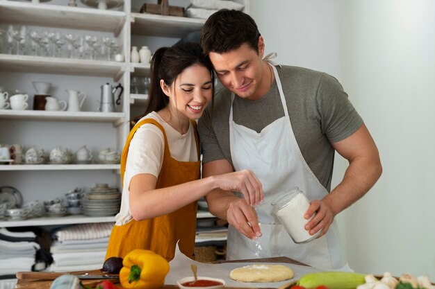 Medium shot people cooking pizza together