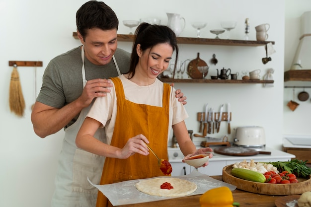 Medium shot people cooking pizza together