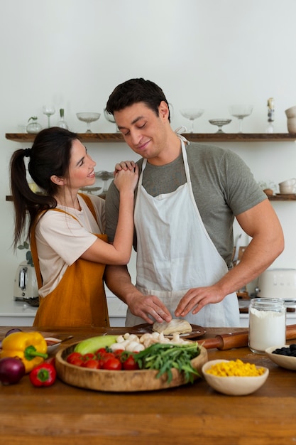 Medium shot people cooking pizza together