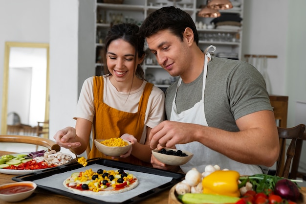 Medium shot people cooking pizza together