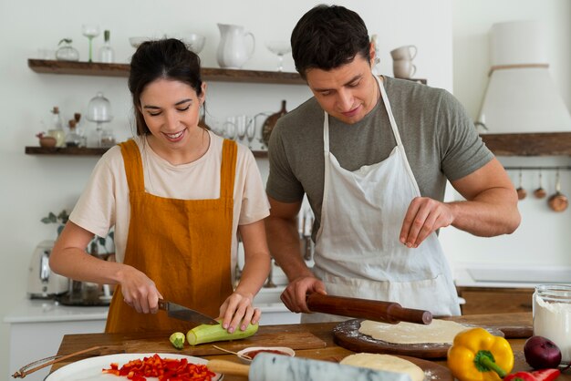 Medium shot people cooking pizza together