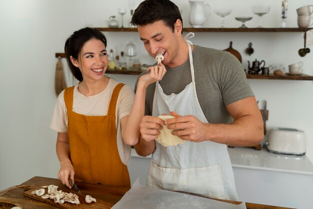 Medium shot people cooking pizza together