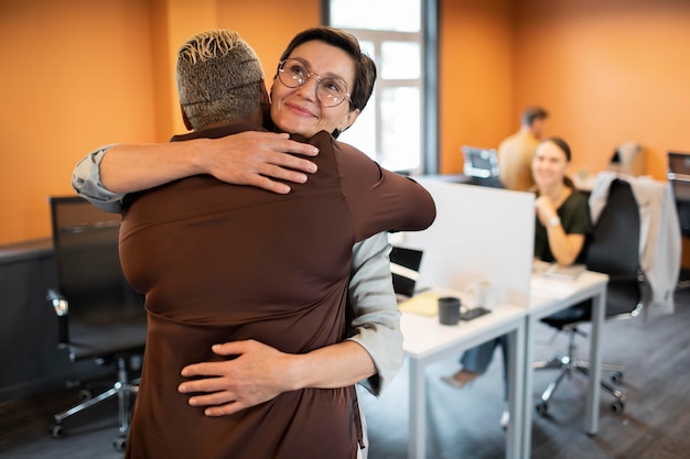 Free photo medium shot people hugging at work