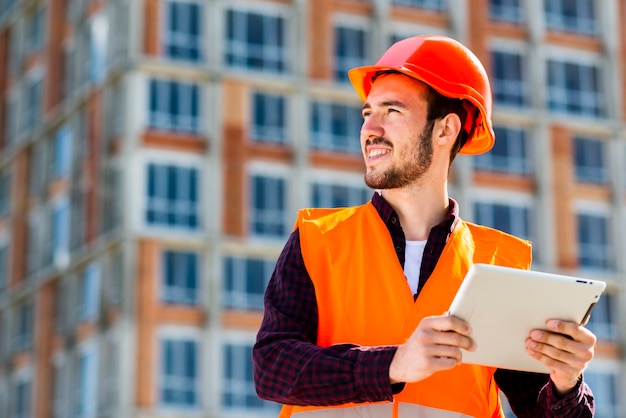 Medium shot portrait of construction engineer holding tablet