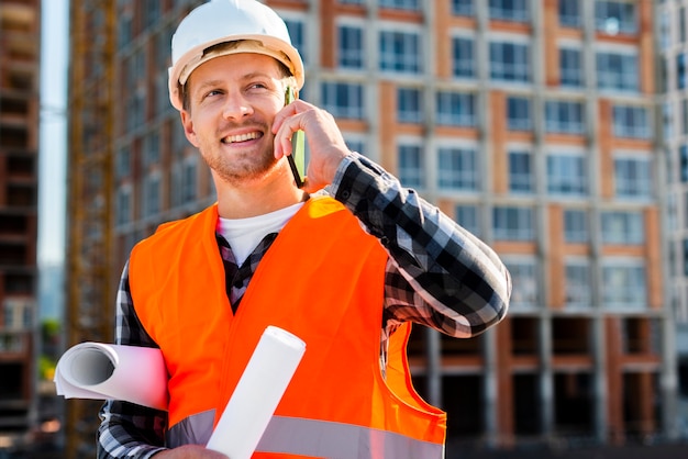 Medium shot portrait of construction engineer talking on the phone