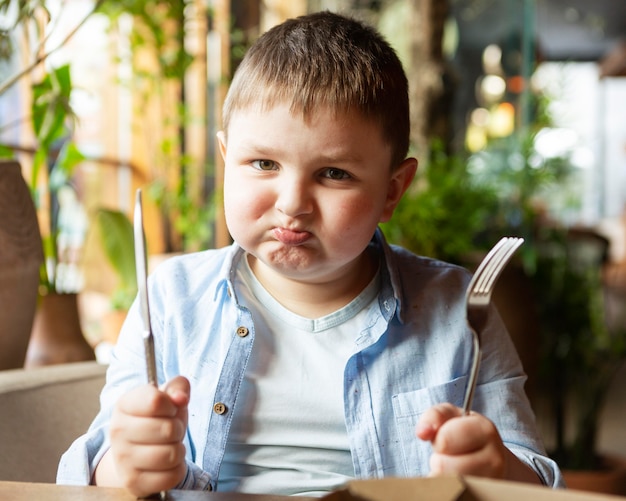 Medium shot sad kid with cutlery