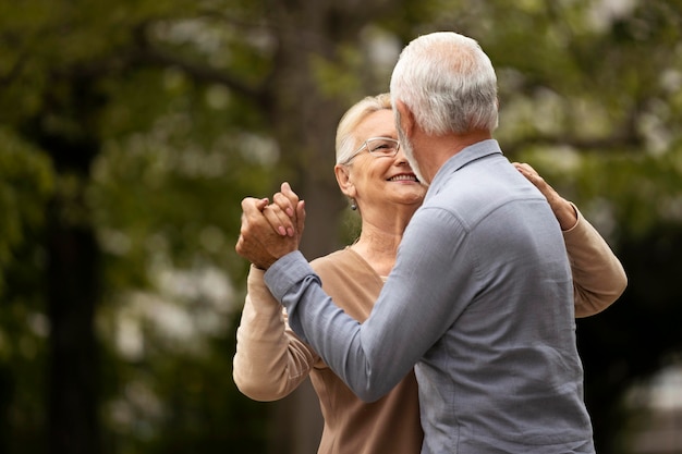 Medium shot senior couple dancing in nature