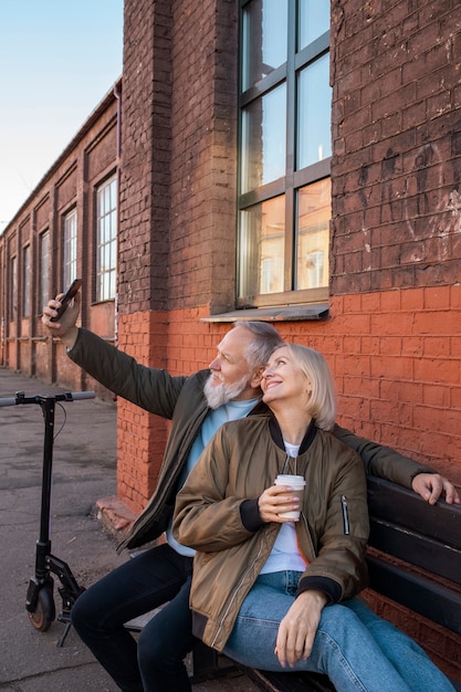 Medium shot senior couple taking selfie on bench