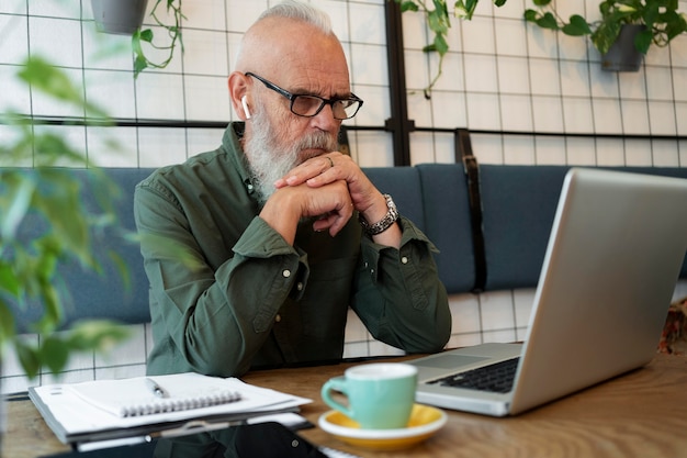 Medium shot senior man studying with laptop