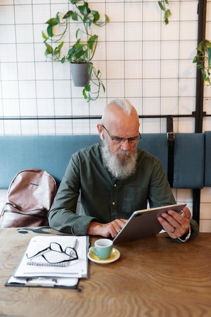 Free Photo medium shot senior man studying with tablet