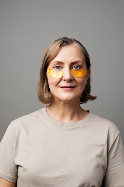 Medium shot senior woman using eye patches