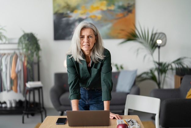 Medium shot senior woman with laptop indoors