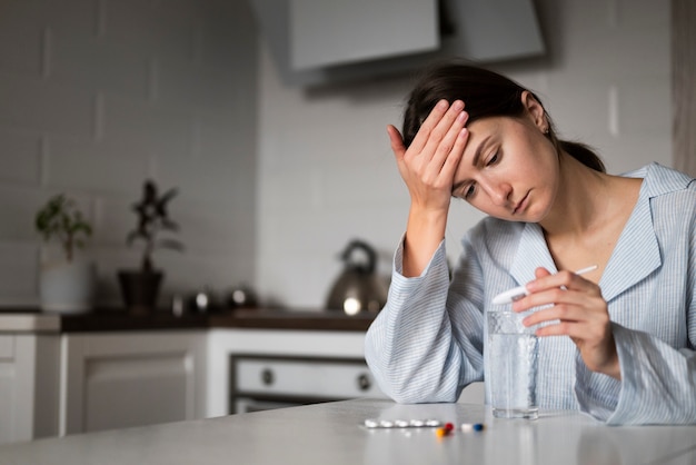 Free photo medium shot sick woman holding thermometer