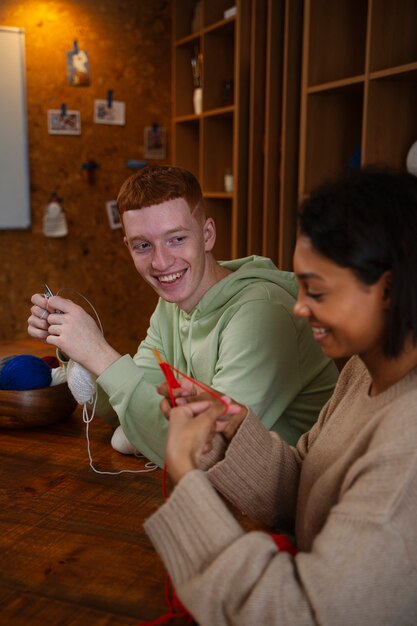 Medium shot smiley adults knitting together