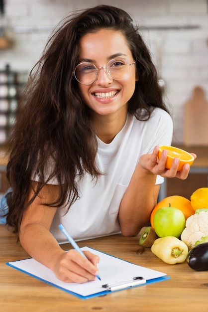 Medium shot smiley brunette woman writing