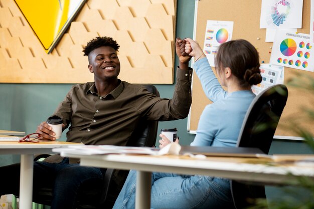 Medium shot smiley colleagues fist bump