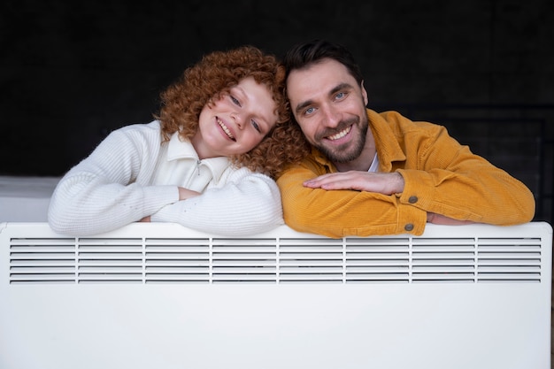 Free photo medium shot smiley couple with heater