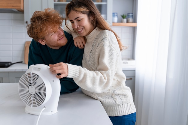 Free photo medium shot smiley couple with small heater