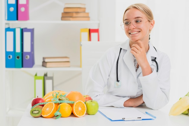 Medium shot smiley doctor with healthy fruits