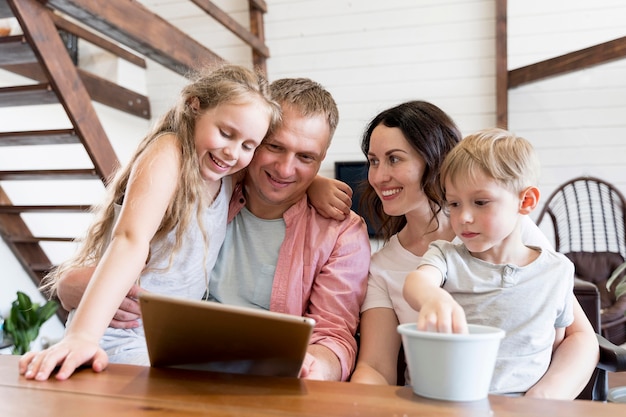 Free photo medium shot smiley family looking at tablet